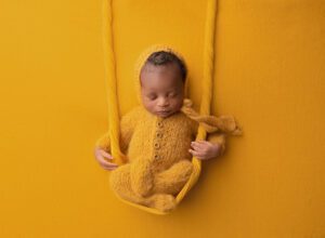 newborn baby posed on a swing