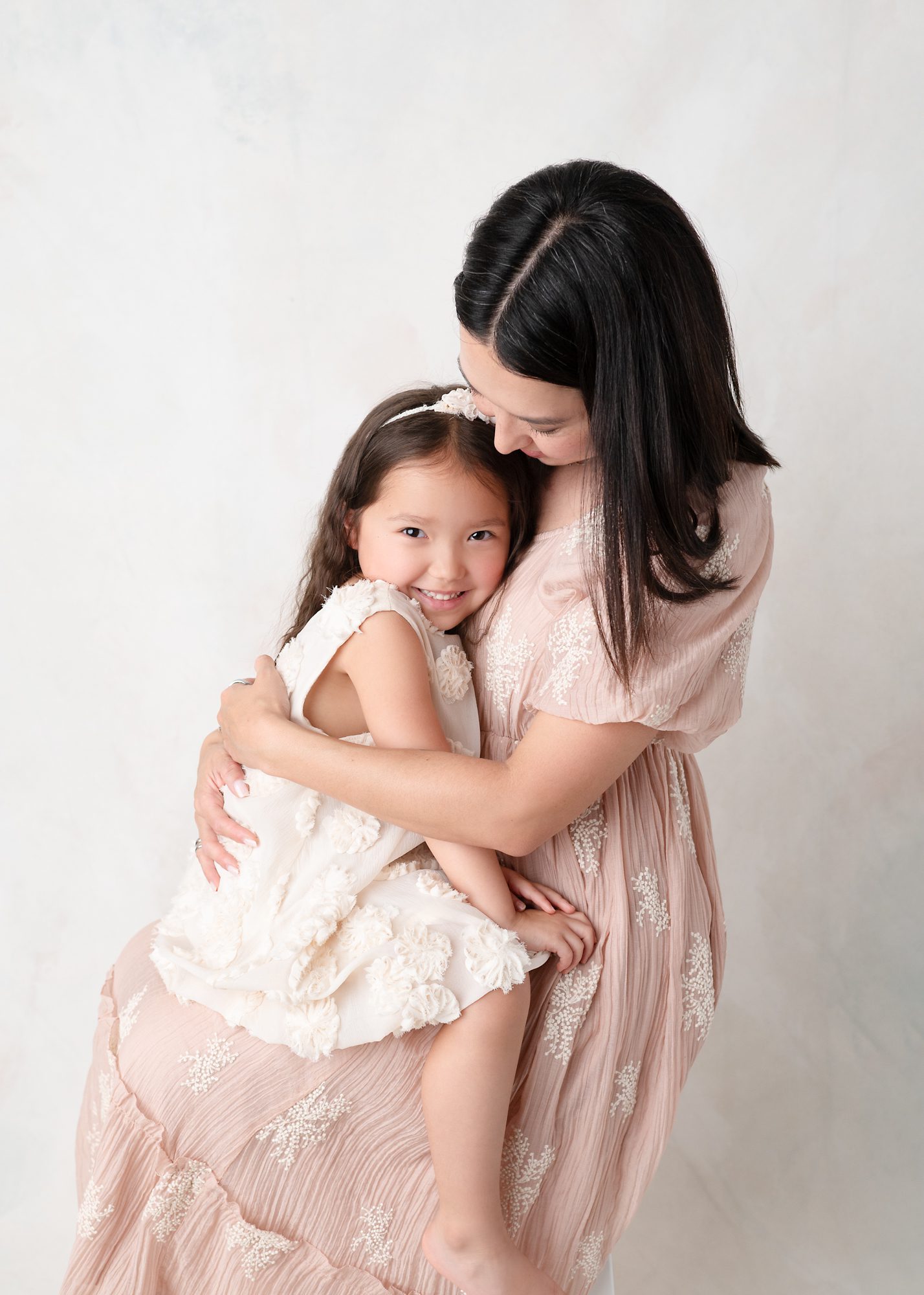 Mommy and me portrait of 5-year-old girl snuggling on her mom's lap